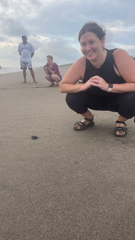 Me squatting down with one of the tiny baby sea turtles in the sand in Las Penitas.