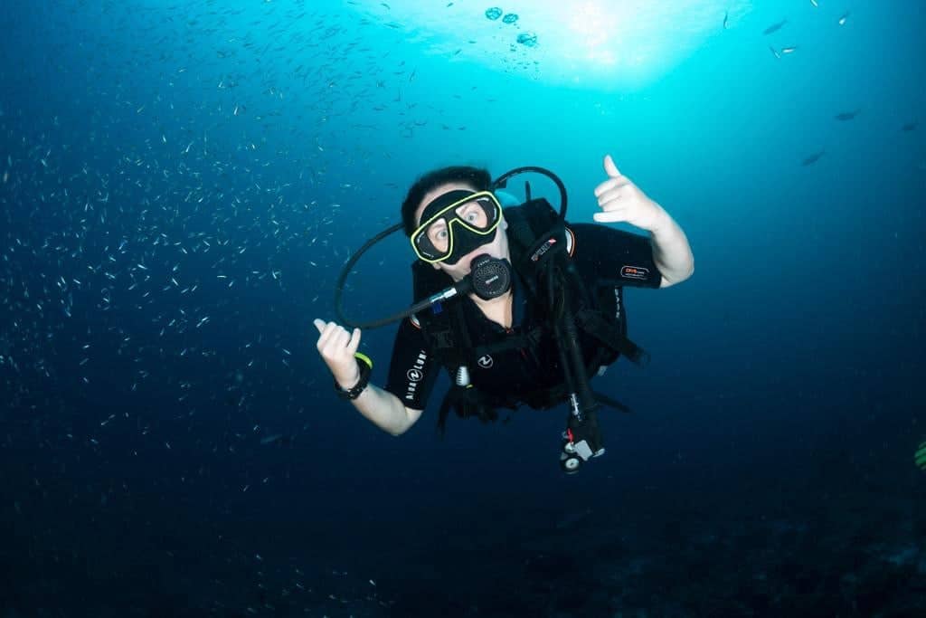 A picture of me scuba diving in very blue water, showing the hang-loose sign - my answer to anyone who asks "Is Honduras Safe?" or "Is Roatan Safe?"