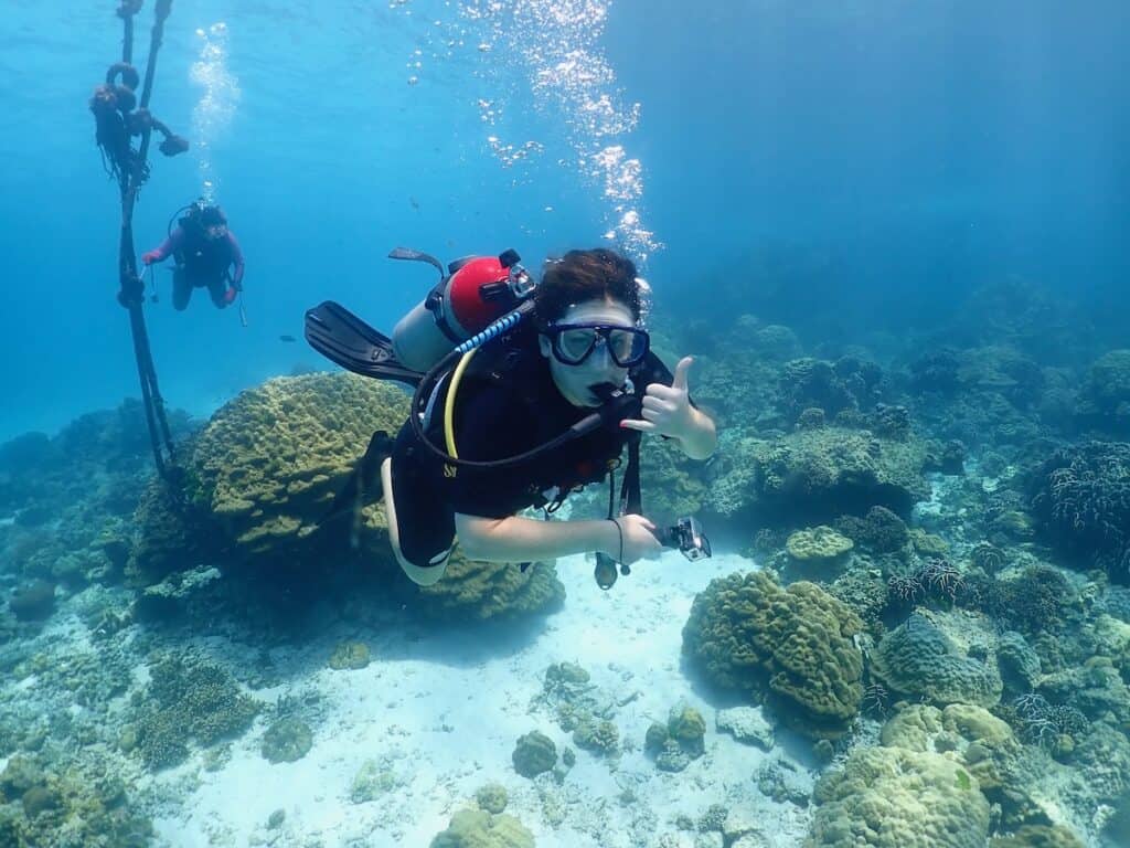 Underwater photo of me scuba diving near Phuket, Thailand. I'm showing the "hang loose" sign, wearing a black wet suit. 