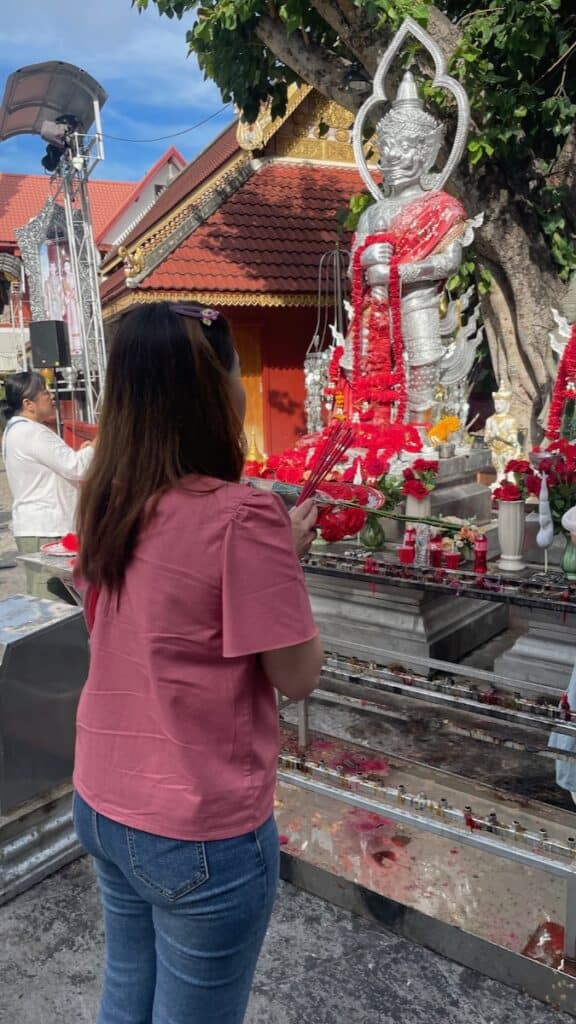 Woman praying in front of a Buddhist shrine just outside the main ordination hall of Wat Sri Suphan, Chiang Mai's silver temple.