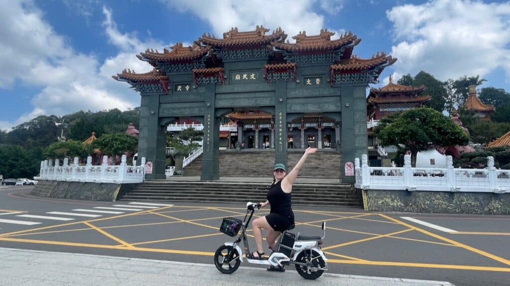 A photo of me on an ebike posing in front of a temple at Sun Moon Lake in Taiwan, before the accident.